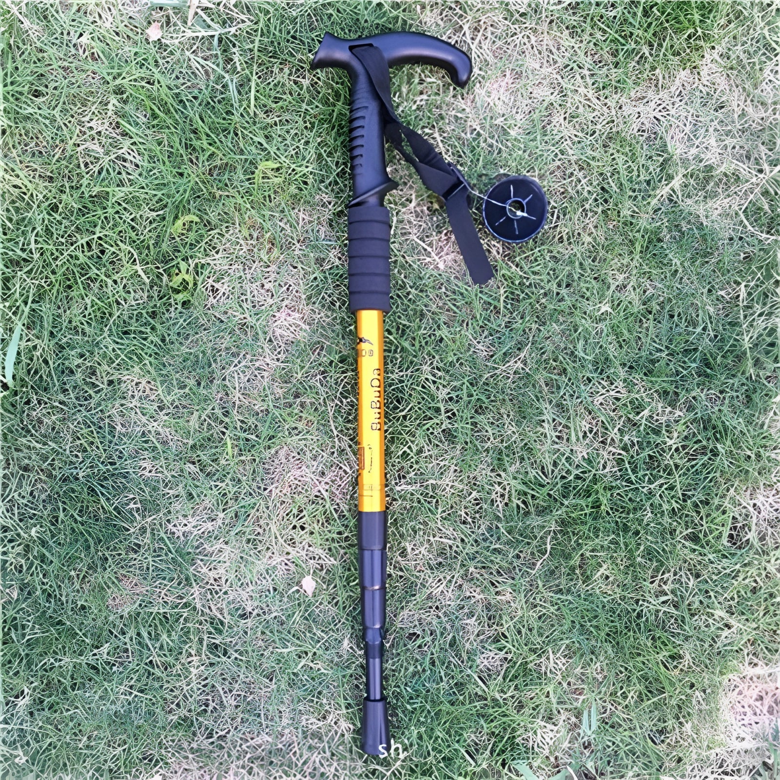 Yellow adjustable shock-absorbing trekking poles with ergonomic L shape handles, displayed on grass.