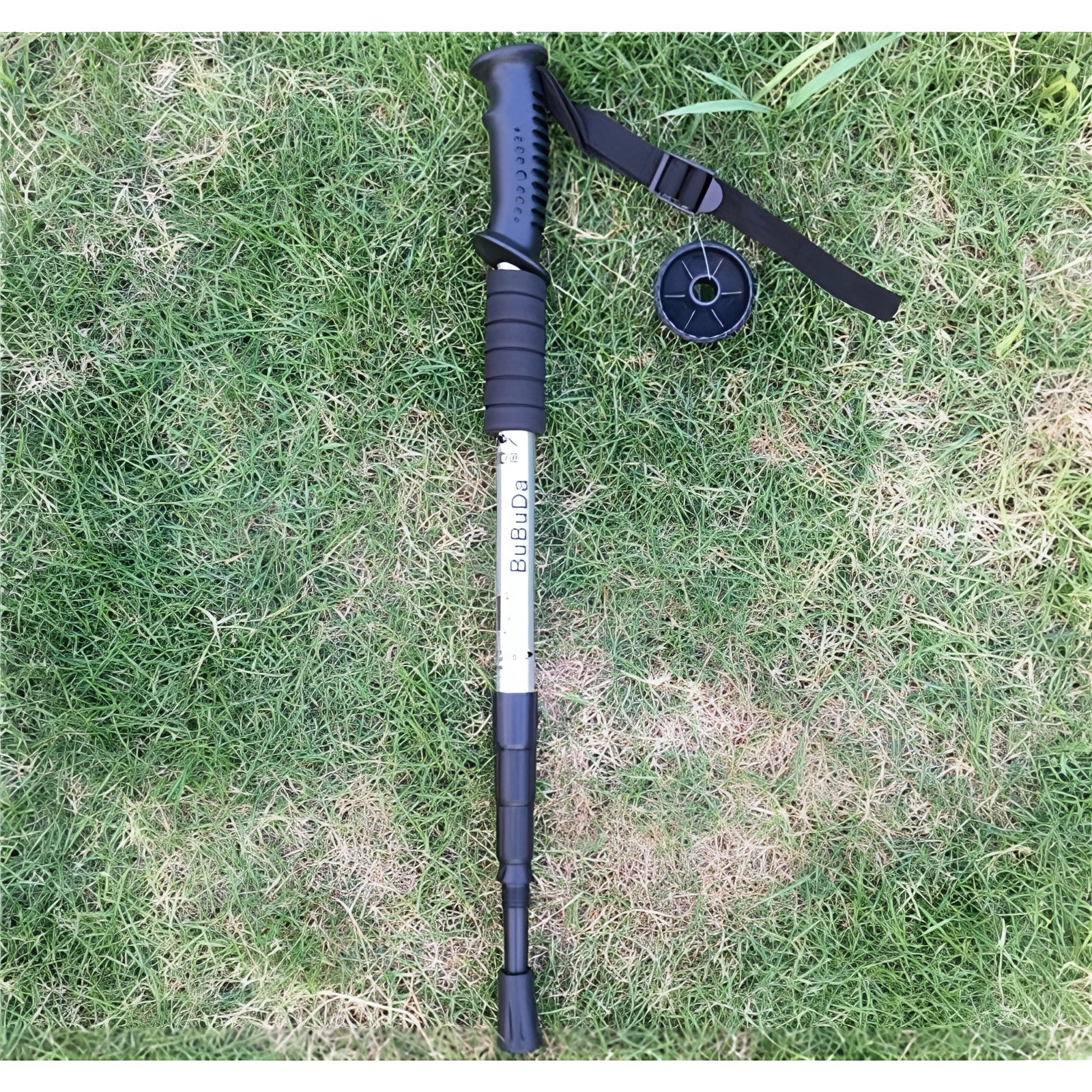 Adjustable shock-absorbing trekking poles in silver with ergonomic straight handles, shown partially collapsed on a grassy surface.