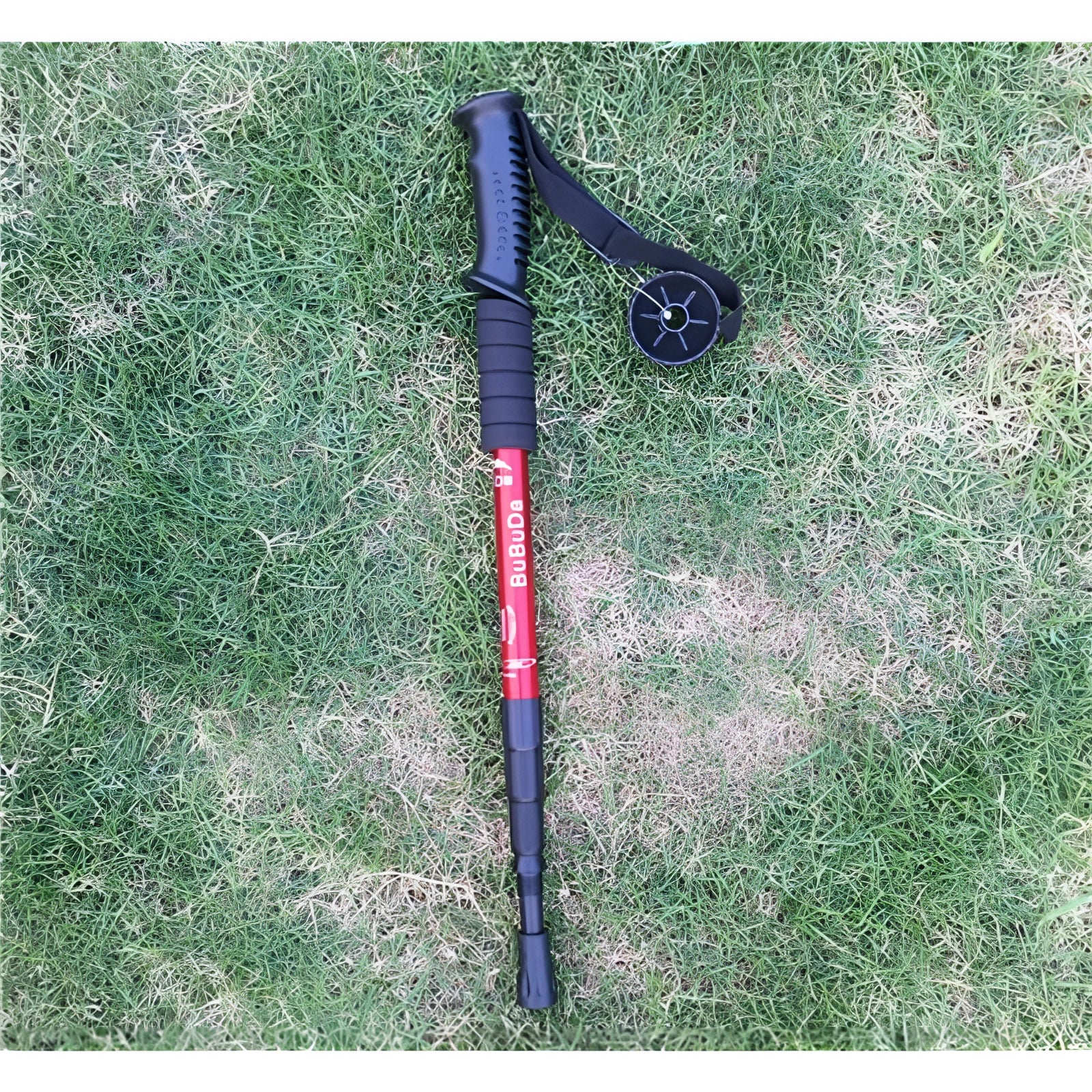 Adjustable red trekking poles with ergonomic handles; lightweight and collapsible design, shown on a grassy surface.