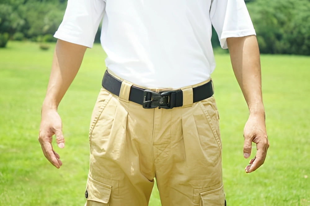 Person wearing an adjustable tactical belt made of durable nylon with a quick-release buckle, shown around the waist over khaki pants in an outdoor setting.