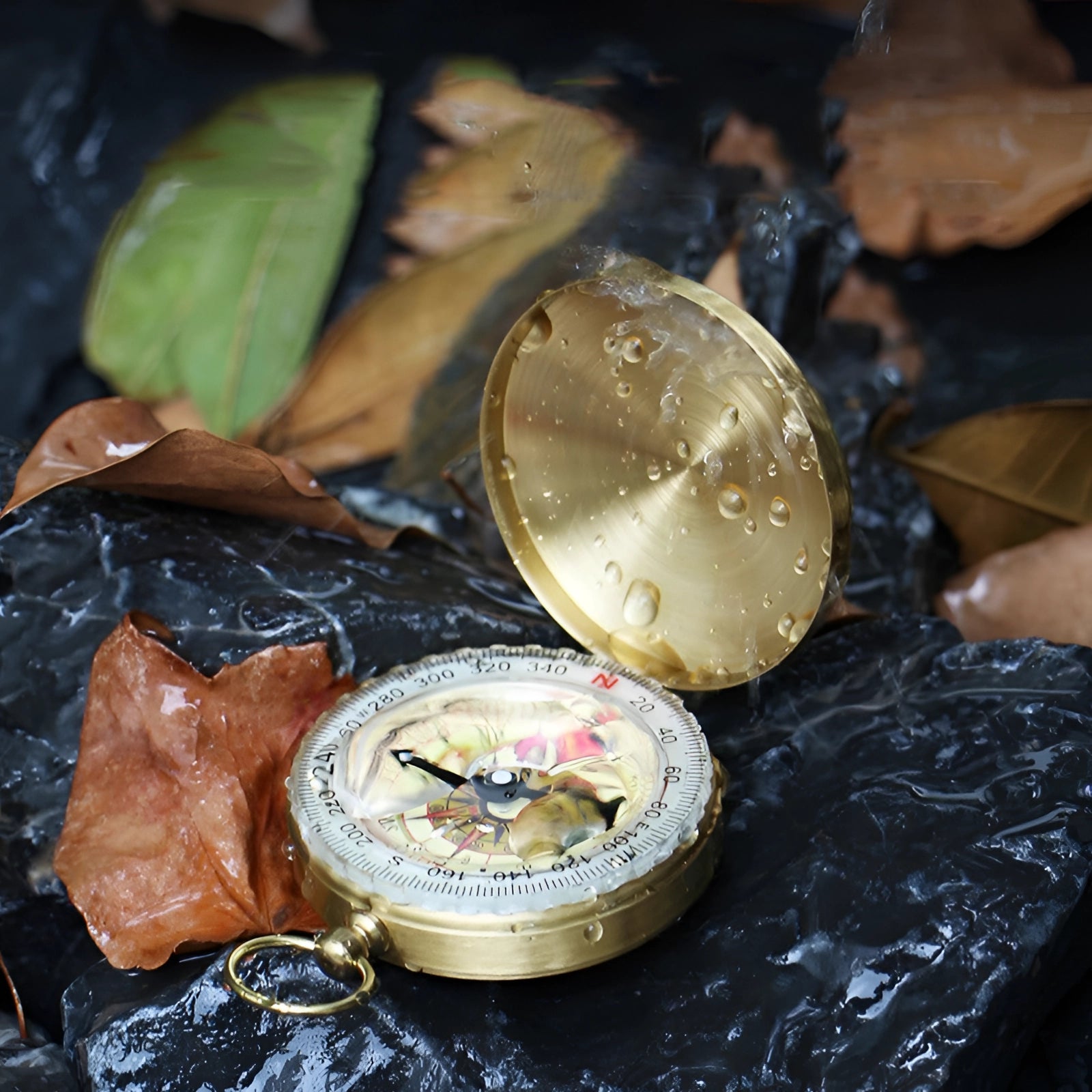 Antique brass pocket compass with a vintage design, featuring a glow-in-the-dark dial, placed on a wooden table.