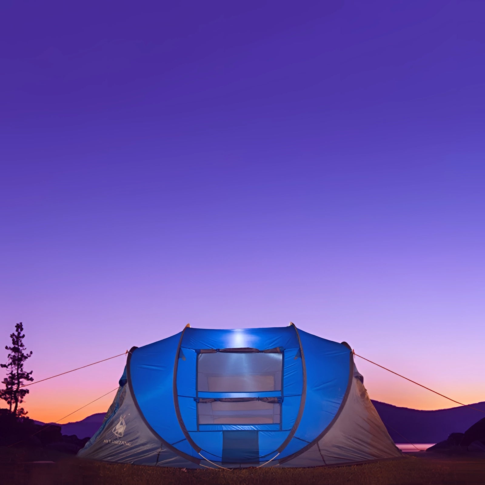 Automatic pop-up blue camping tent set up in an outdoor landscape with trees and clear sky in the background.