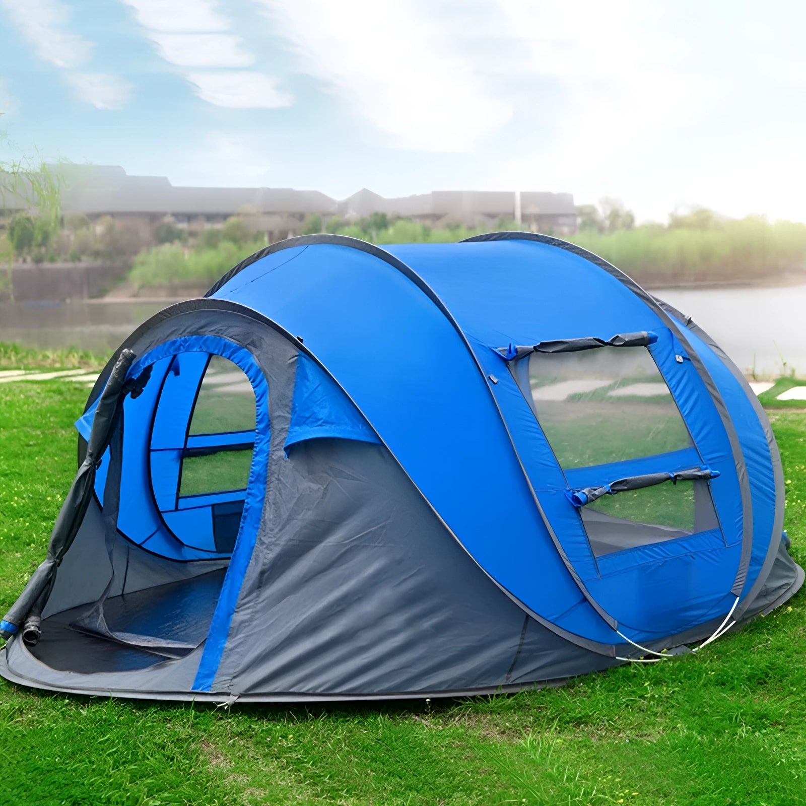 Automatic blue pop-up camping tent set up on a grassy plain under a partly cloudy sky.