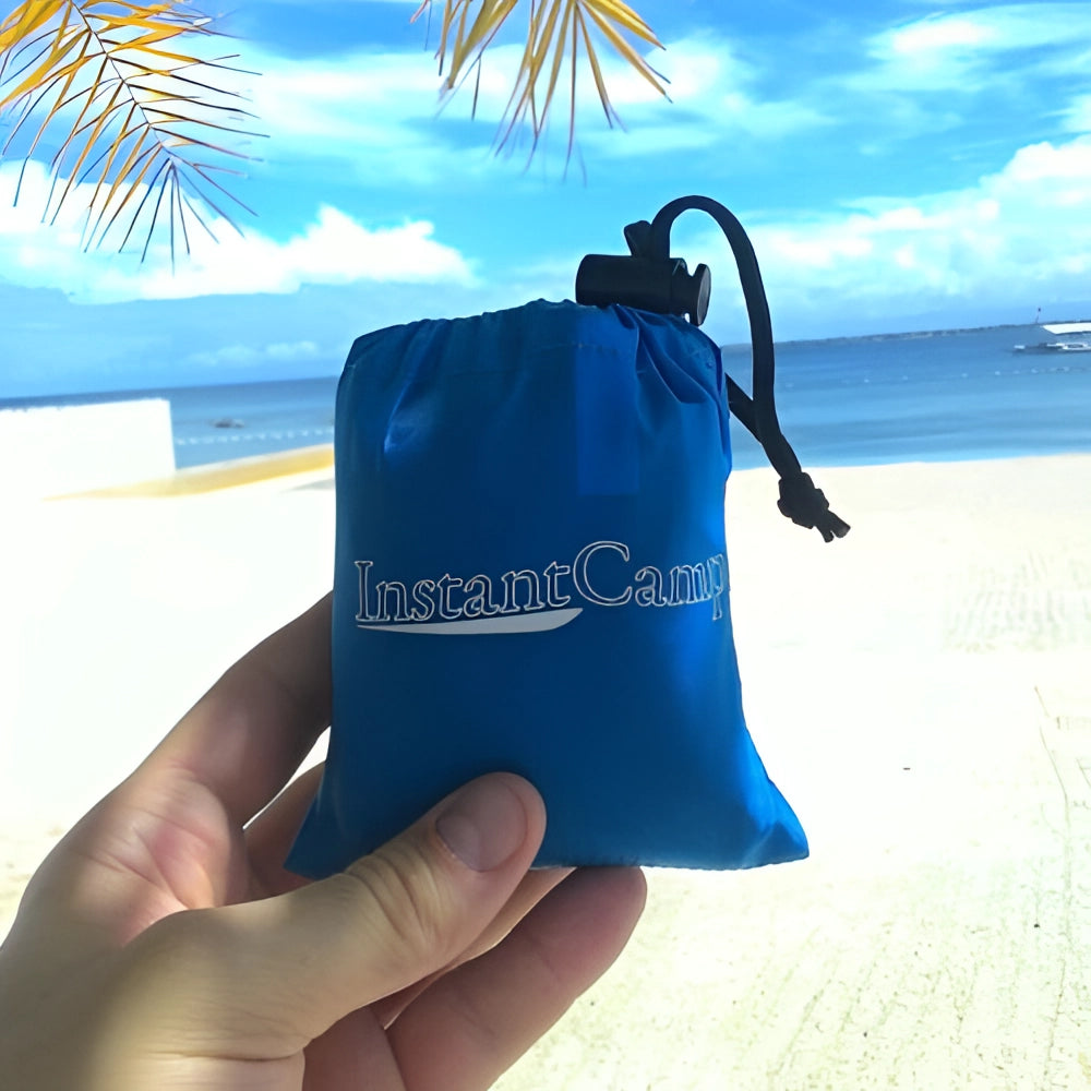 Compact lightweight inflatable camping pillow in blue, shown inflated against a sky background with clouds.