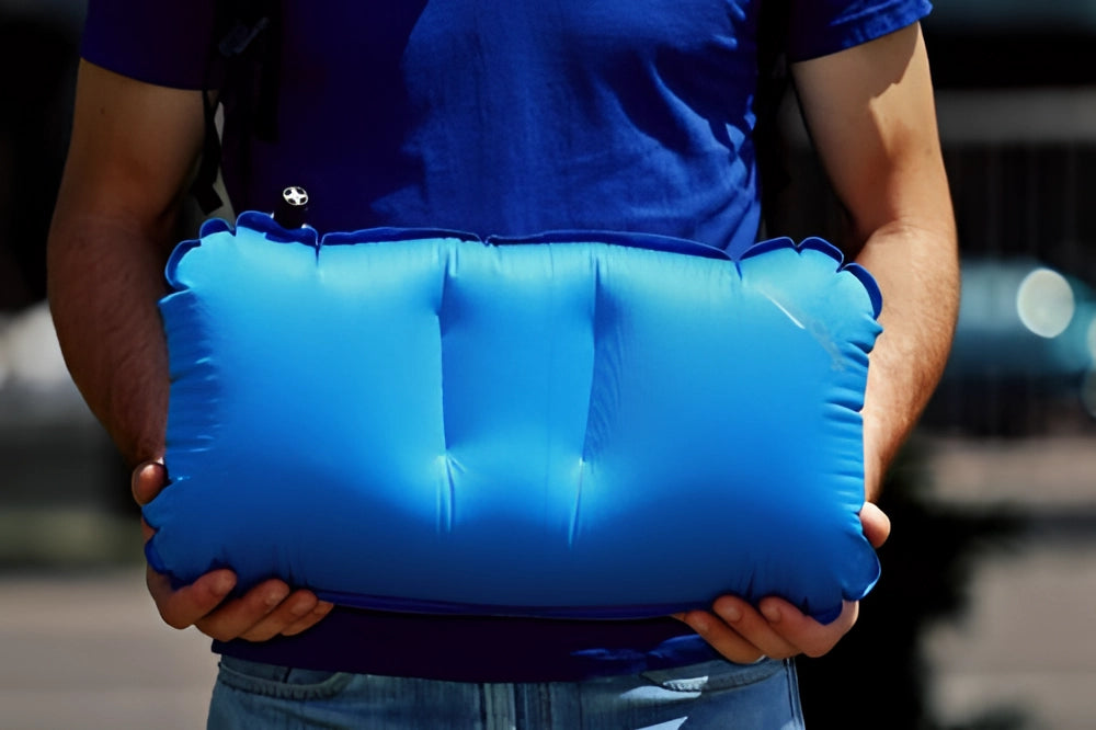 Compact lightweight blue inflatable camping pillow, easy to inflate, portable, shown in a rolled-up state.