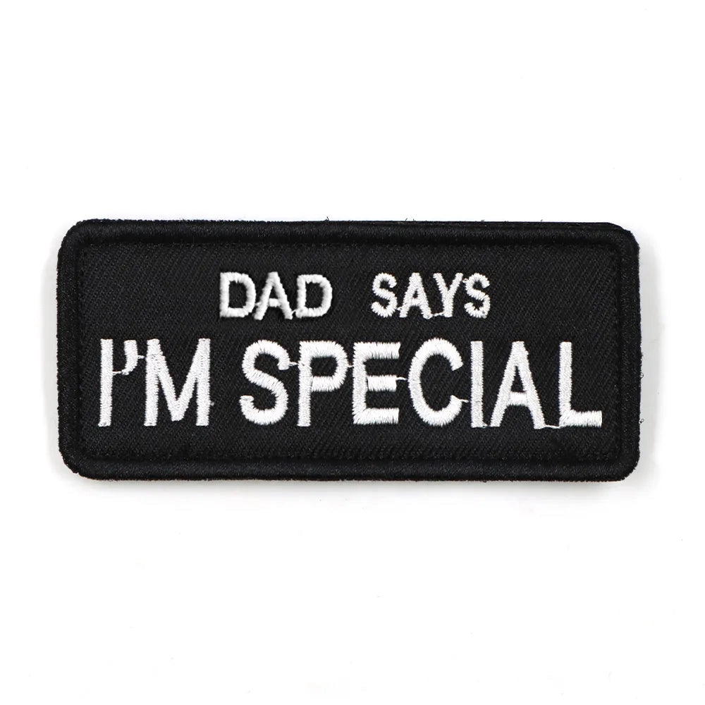 A rectangular, electric blue harness patch with the text "DAD Says I'M Special" in white font.