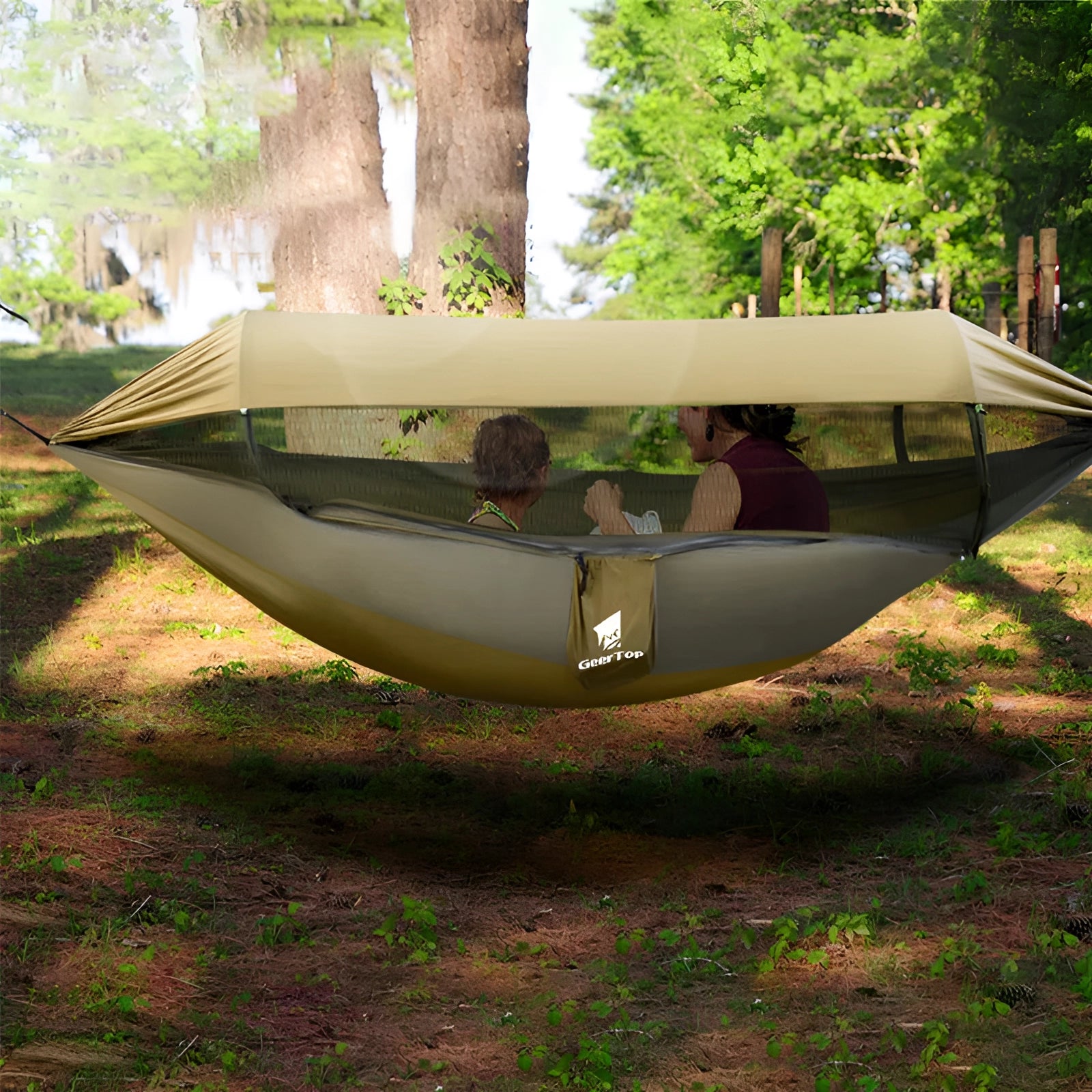 Enclosed mosquito-proof outdoor mesh hammock with dual-entry, set up in a shaded wooded area, surrounded by trees and plants, illustrating a leisure and recreational outdoor setting.