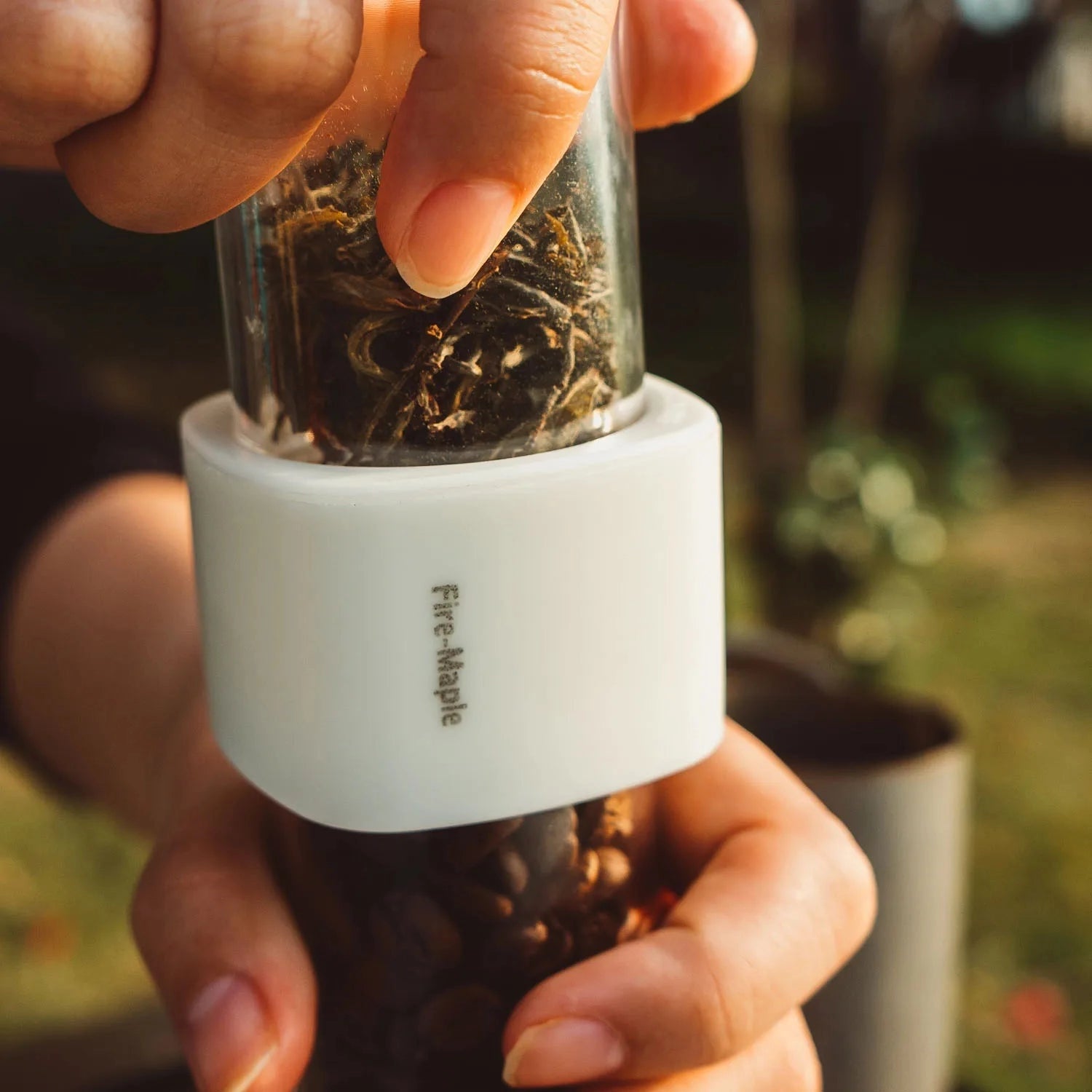 Hand holding FireMaple Airtight Coffee & Tea Container, demonstrating its compact and stylish design.