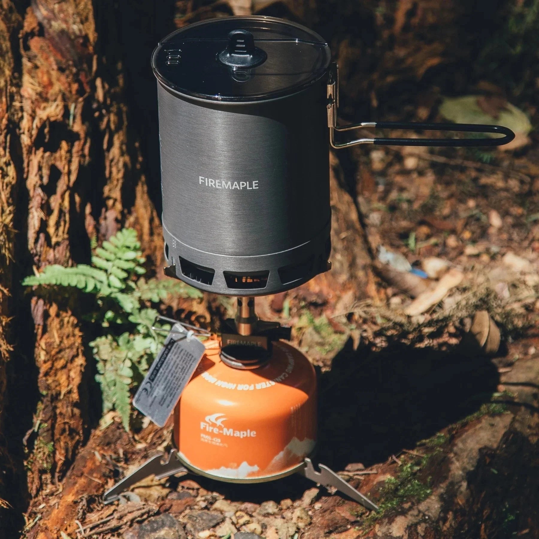 Ultralight and durable titanium gas canister stand for outdoor use, designed by FireMaple, shown in a sleek, cylindrical form ideal for stabilizing fuel canisters during camping or backpacking adventures.