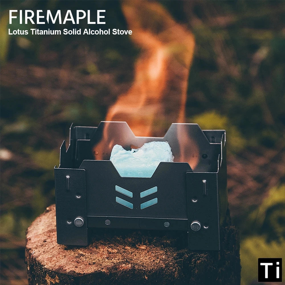 FireMaple Lotus Titanium Ultralight Alcohol Stove set up in a camping setting with natural landscape elements such as grass and trees in the background.