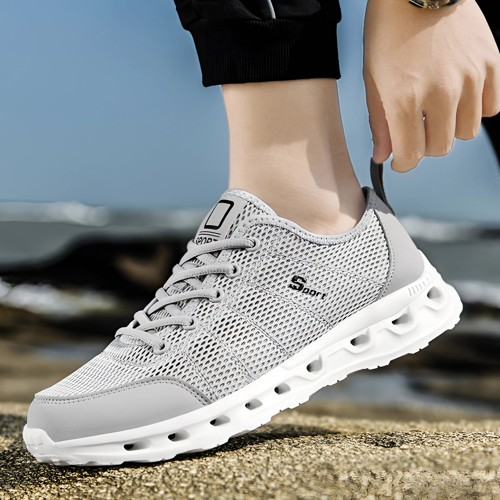 Lightweight breathable black and white mesh running shoes, cushioned and durable, shown on feet in a casual sportswear setting.