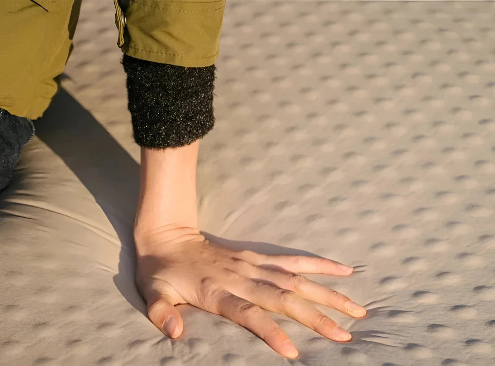 Person demonstrating the compactness of the Naturehike Ultralight Self-Inflating Camping Pad by holding it and showing its size with their fingers, set against a natural outdoor background.