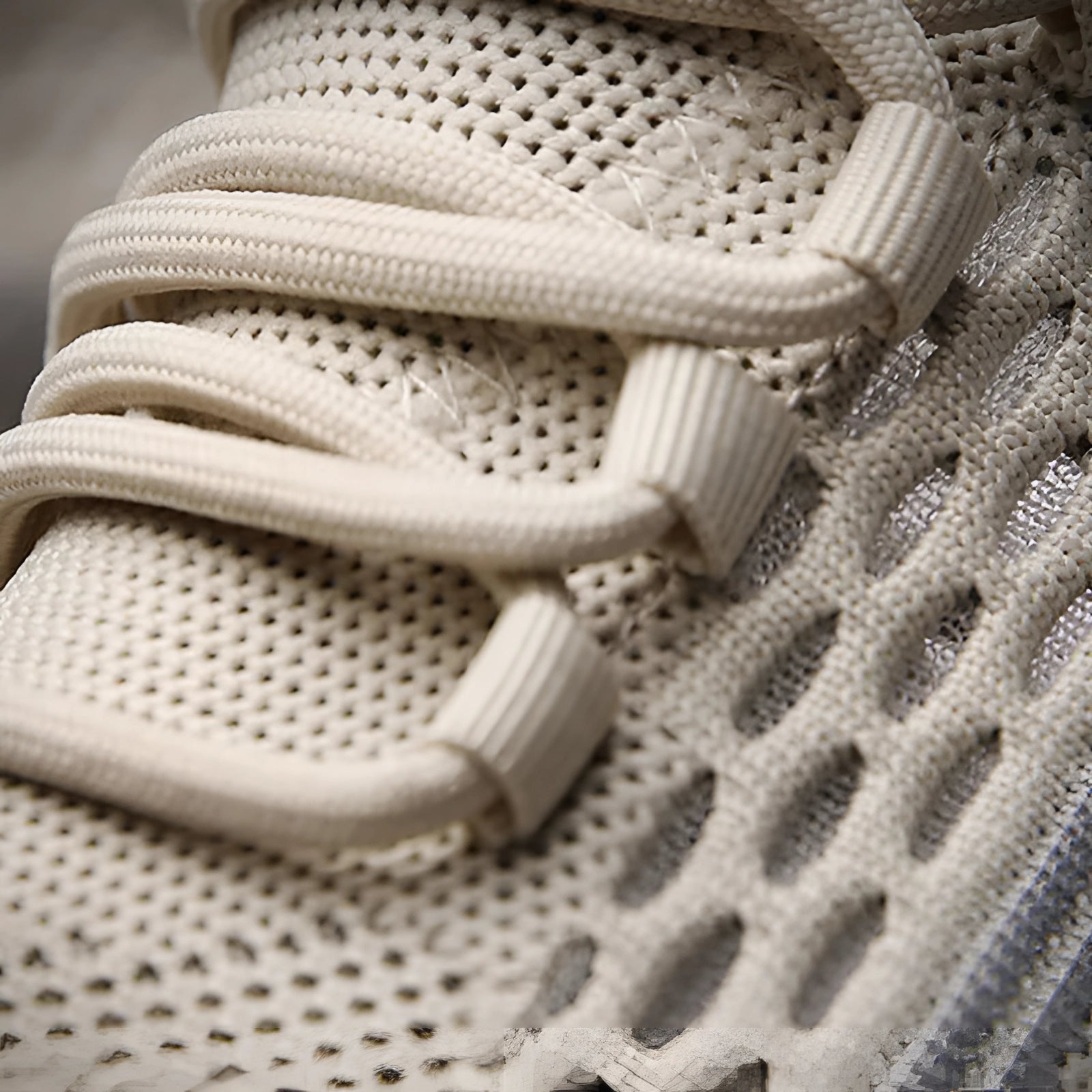 Beige knit sneakers designed by OULYLAN, featuring a lightweight and breathable material, ideal for athletic use; close-up view showcasing the intricate pattern and grey textile accents.