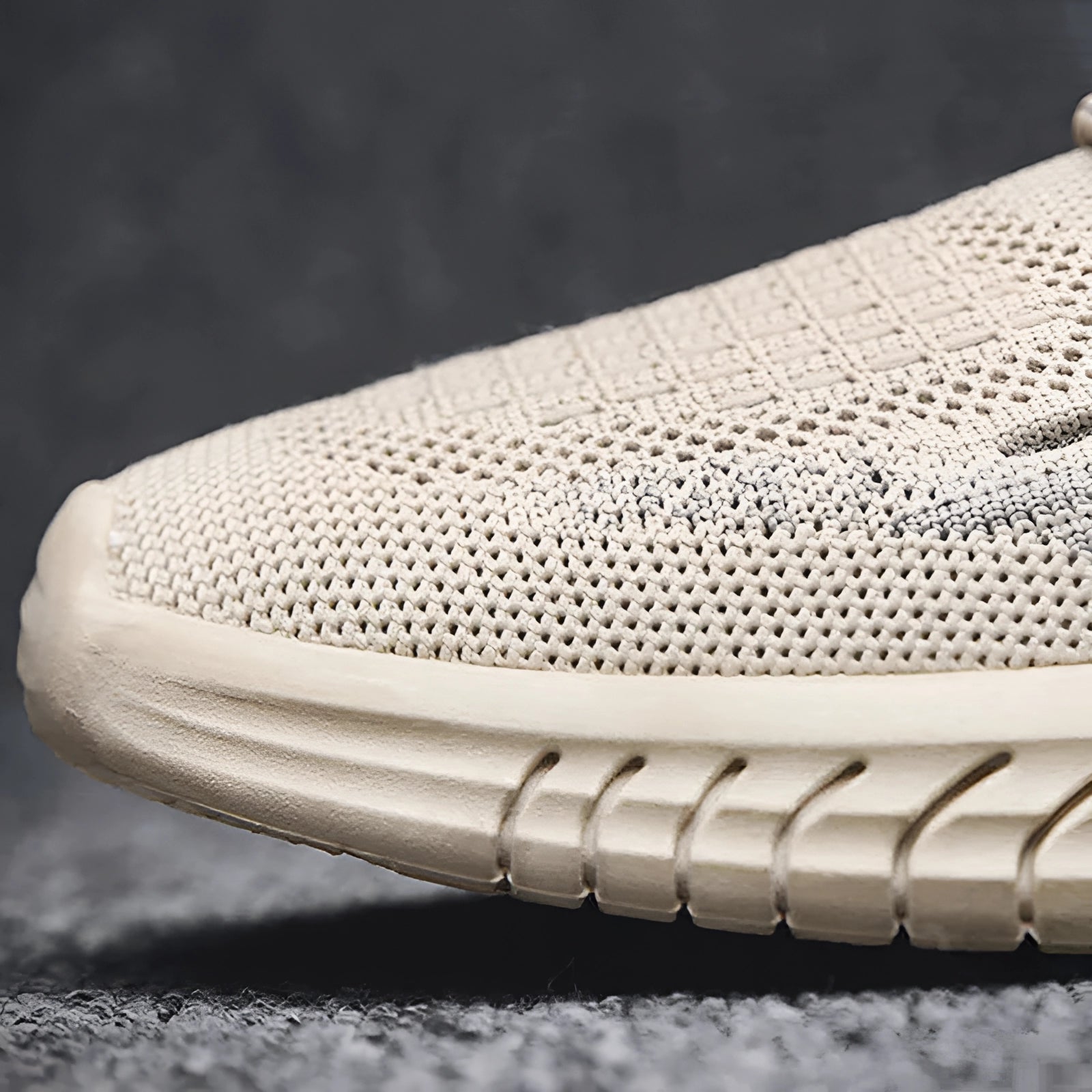 Beige knit sneakers designed for lightweight and breathable comfort, featuring a mesh pattern, suitable for outdoor walking and athletic activities, displayed on grass.