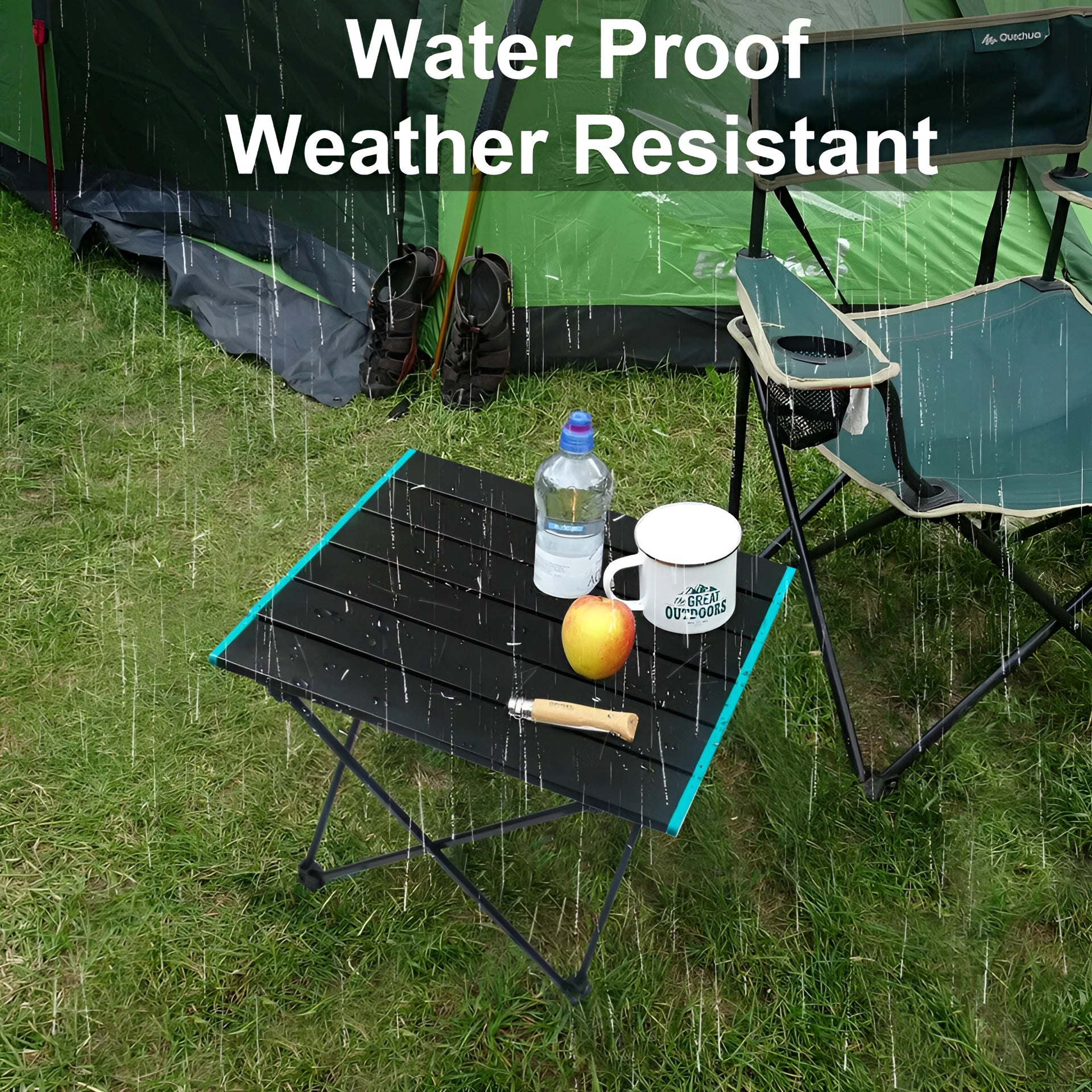 Portable black aluminum folding camping table set up on grass with carrying bag nearby, surrounded by lawn and recreational items like a chair under shade.