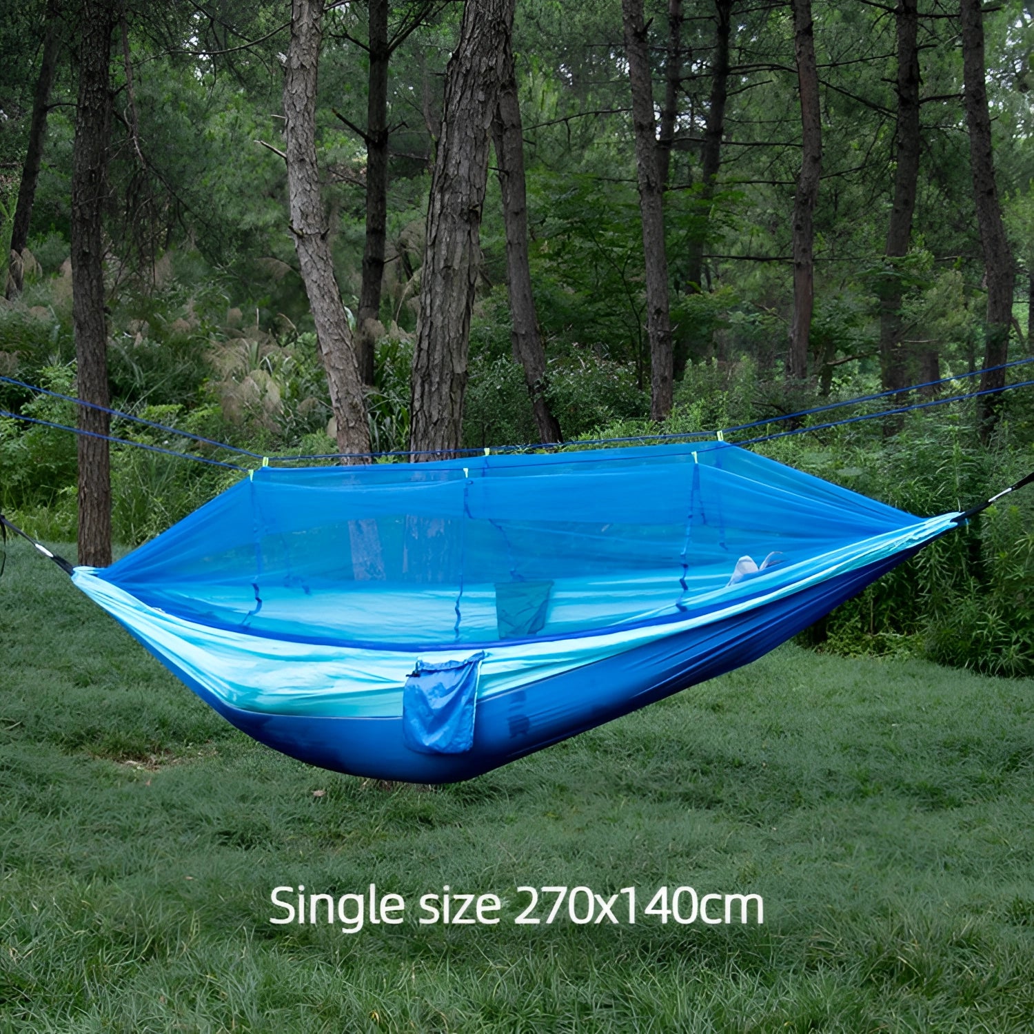 Portable double nylon camping hammock with mosquito net and tree straps set up between two trees in a grassy, shaded area.