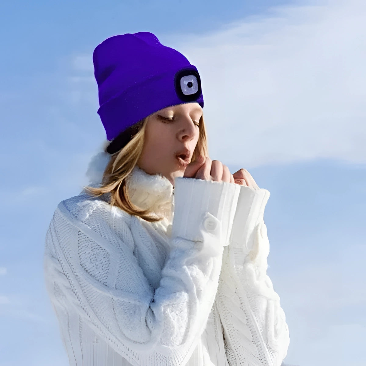 Unisex rechargeable LED beanie hat worn by a happy person outdoors, featuring a bright light in the front, against a sky with scattered clouds.