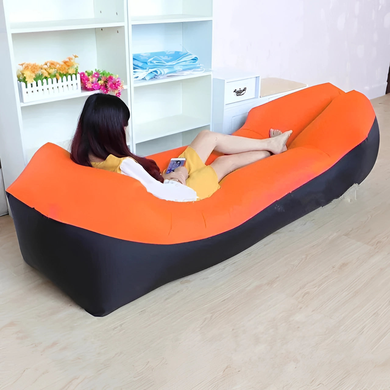 Orange waterproof outdoor inflatable sofa, portable quick-inflate air couch, placed on hardwood flooring.