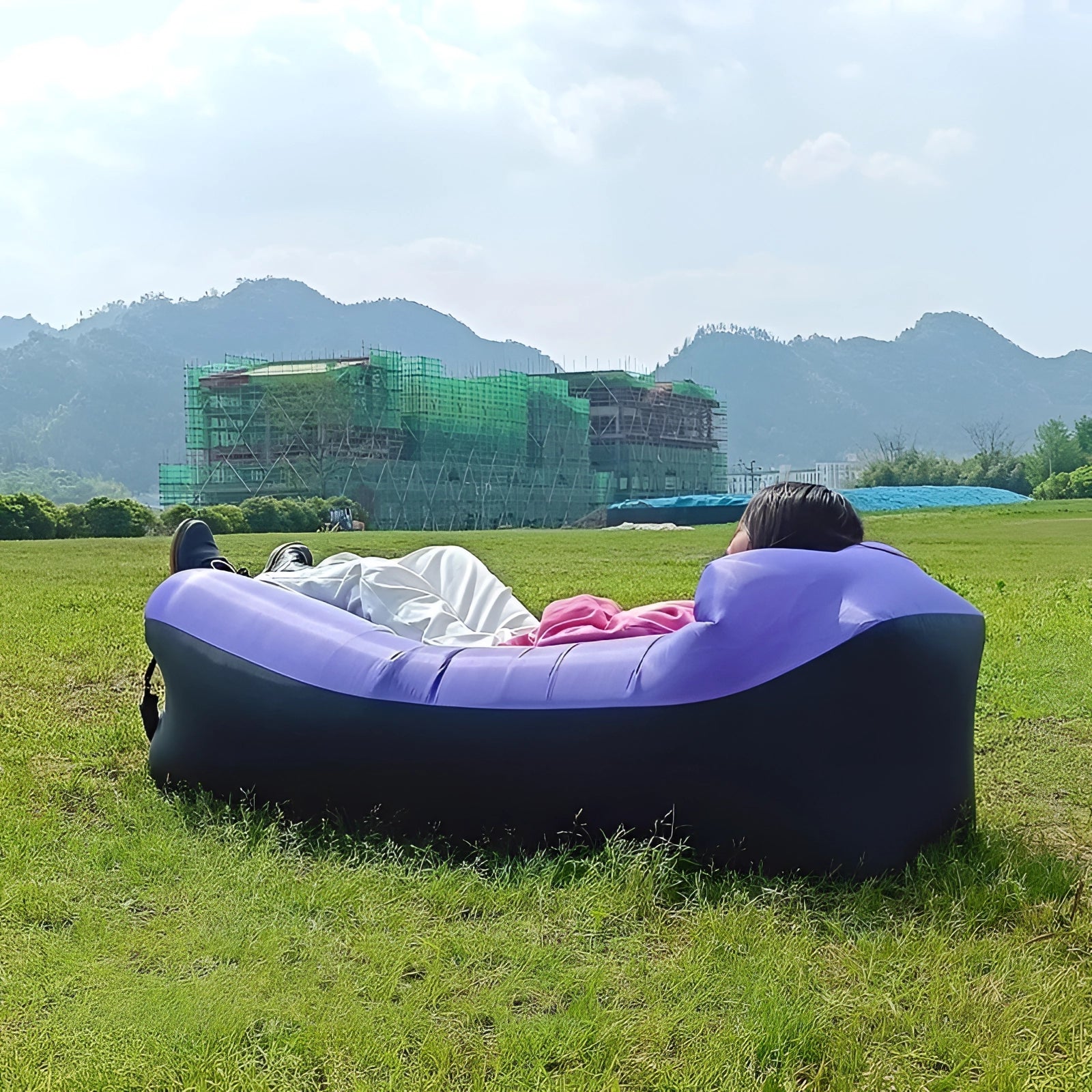 Purple Waterproof Outdoor Inflatable Sofa placed on grass with a scenic backdrop of mountains, sky, and clouds.