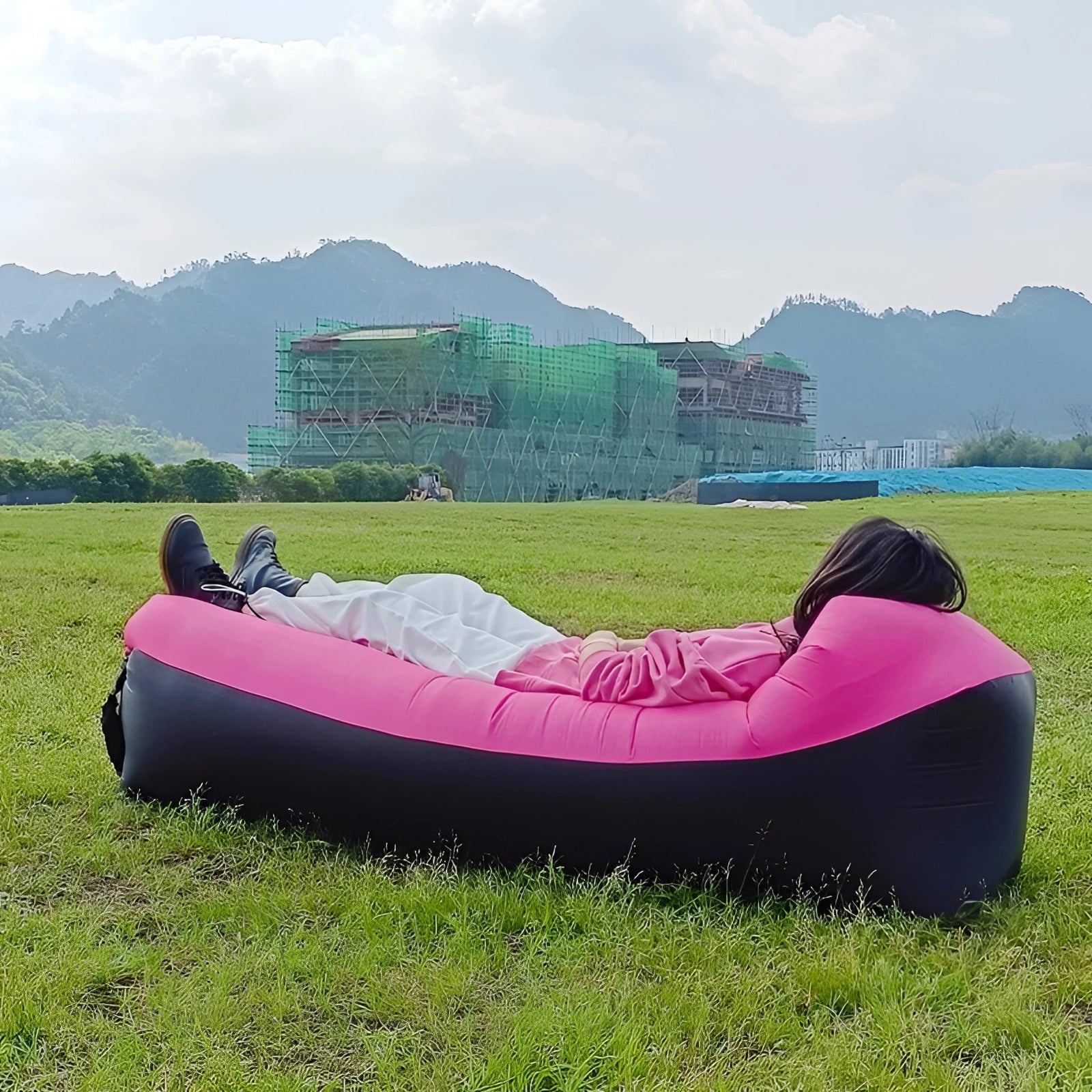 Waterproof outdoor inflatable sofa set up on grass with a scenic background of mountains, sky, and clouds, ideal for leisure and recreation.